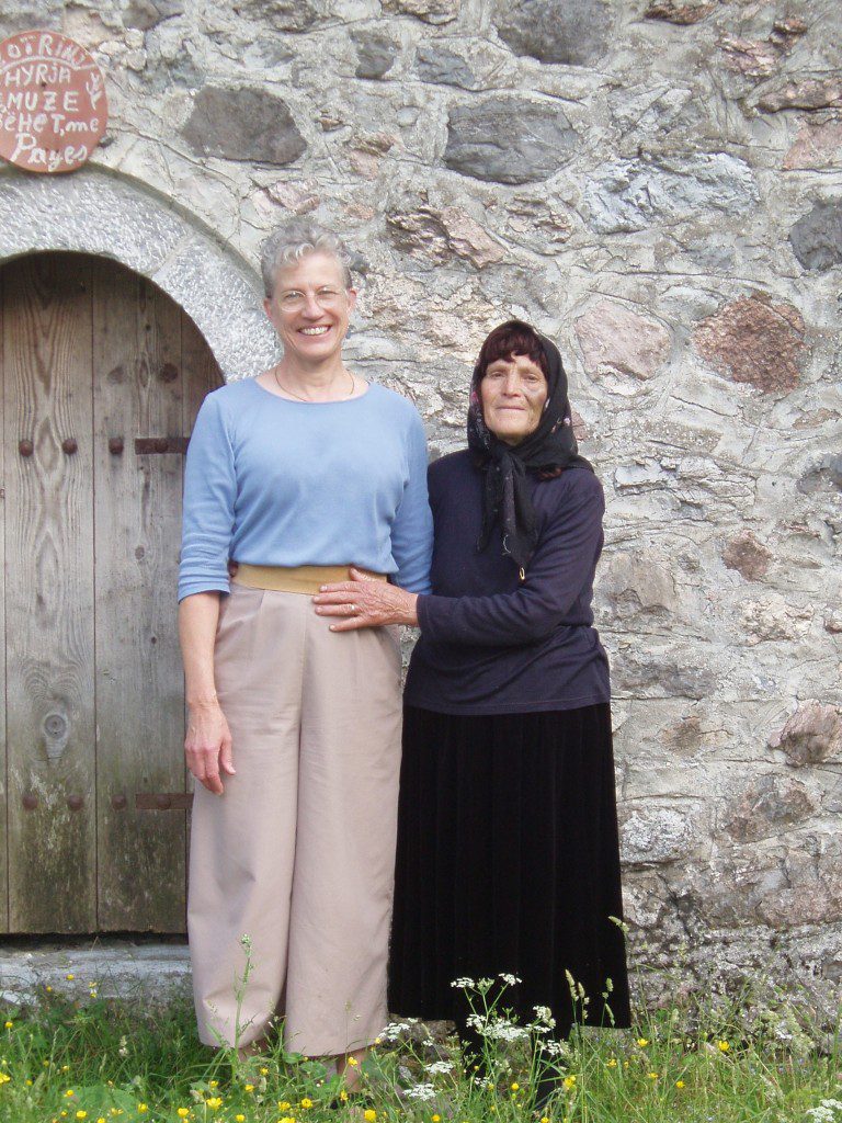 Two women standing by a stone wall