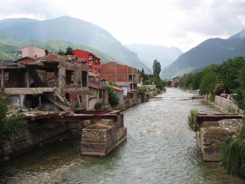 Partially destroyed buildings by riverside.
