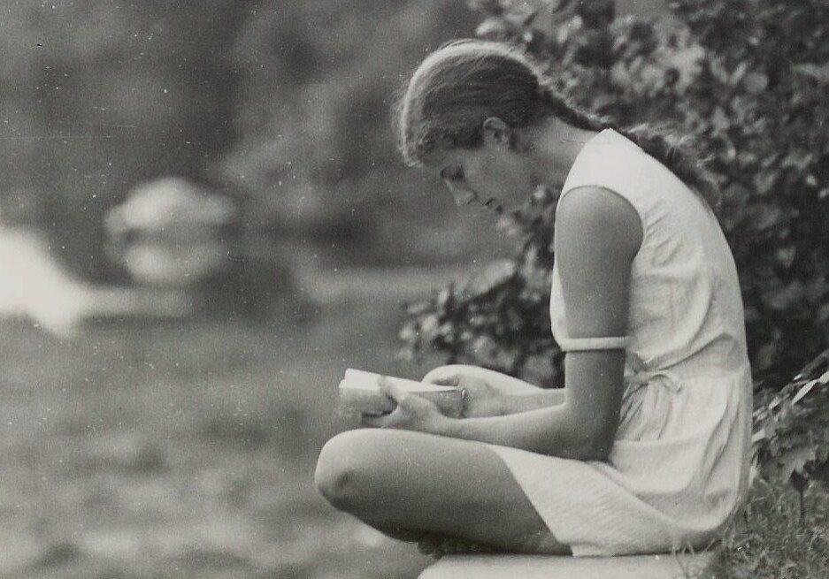 Girl sitting outdoors with book